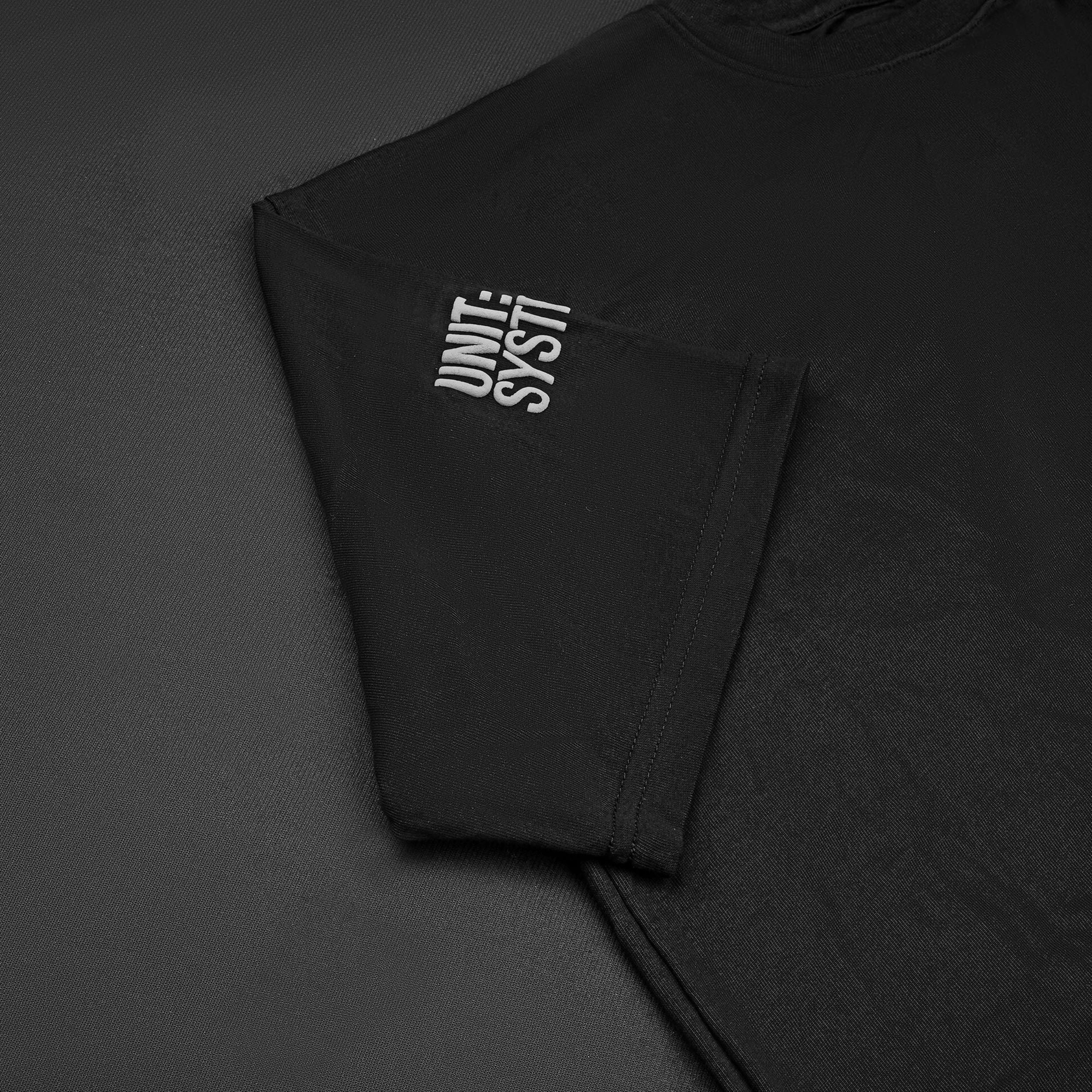 OPERATOR_77 OVERSIZED TEE — WAR BLACK — Flat-lay close-up, black tee UNIT: SYSTI embroidered/printed sleeve text detail