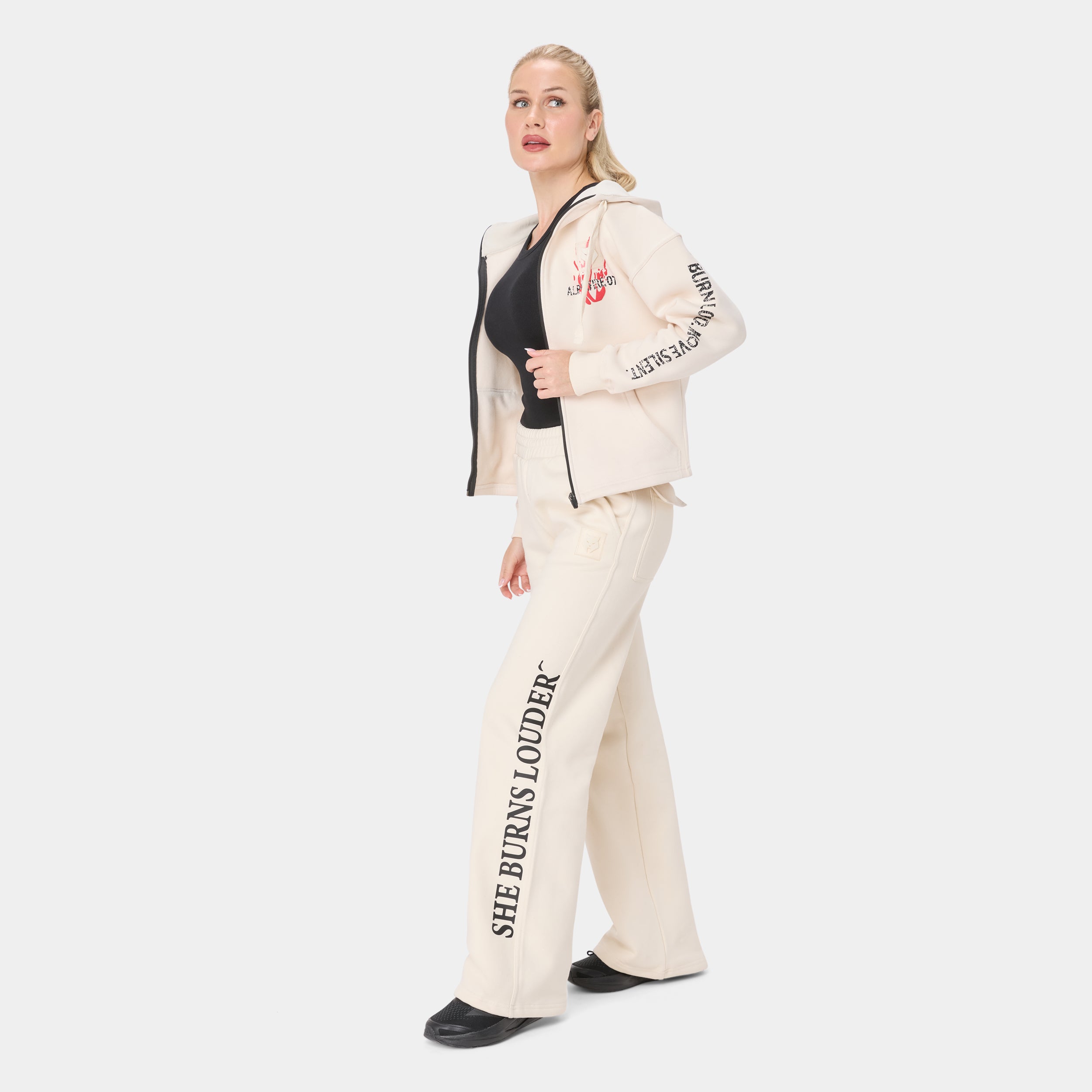 ALPHAFIRE BOTTOM — TACTICAL BEIGE — Side/walking view full body, cream tracksuit with SHE BURNS LOUDER leg text and BURN