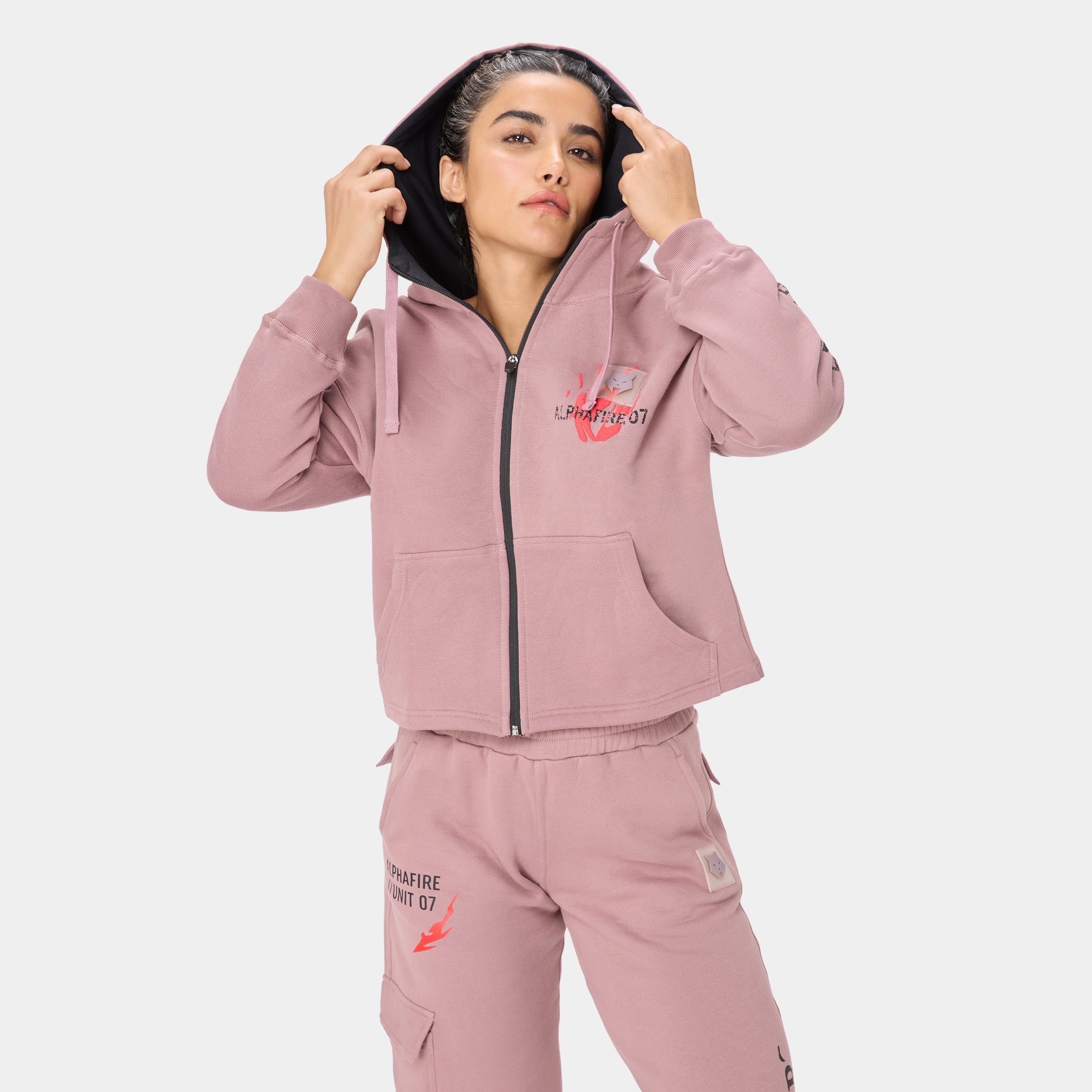 ALPHAFIRE CROP HOODIE — STORM ROSE — Front close-up torso, dusty pink hoodie with model holding hood up, Alphafire 07 chest