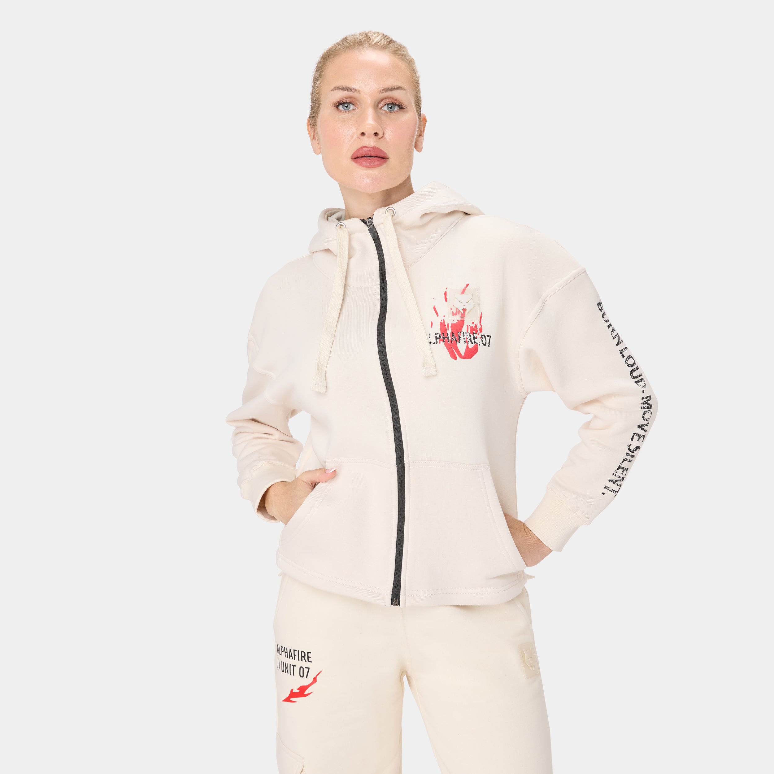 ALPHAFIRE CROP HOODIE — TACTICAL BEIGE — Front view waist-up, cream zip hoodie with hands in pocket and Burn Loud Move Silent