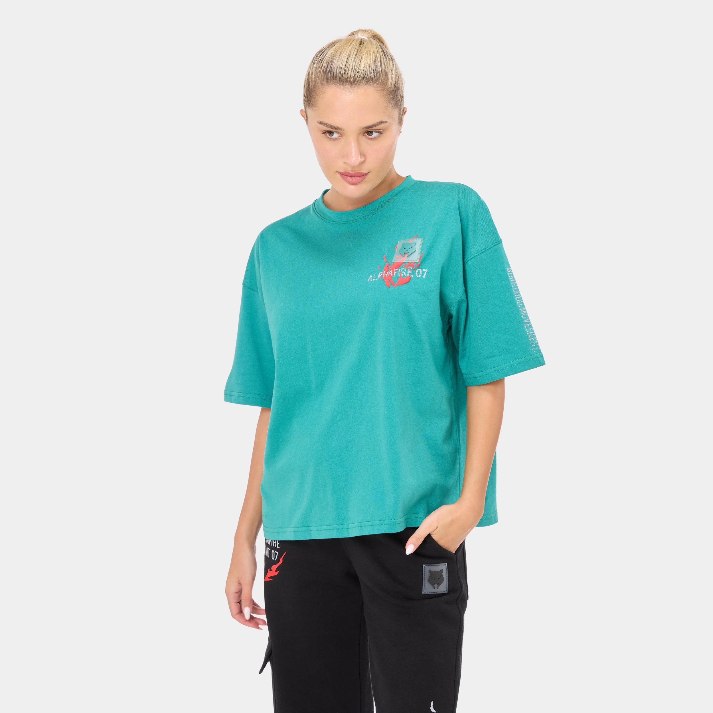 ALPHAFIRE OVERSIZED T-SHIRT — ROUGE GREEN — Front ¾ close-up, teal oversized tee with Alphafire 07 chest logo, model looki...