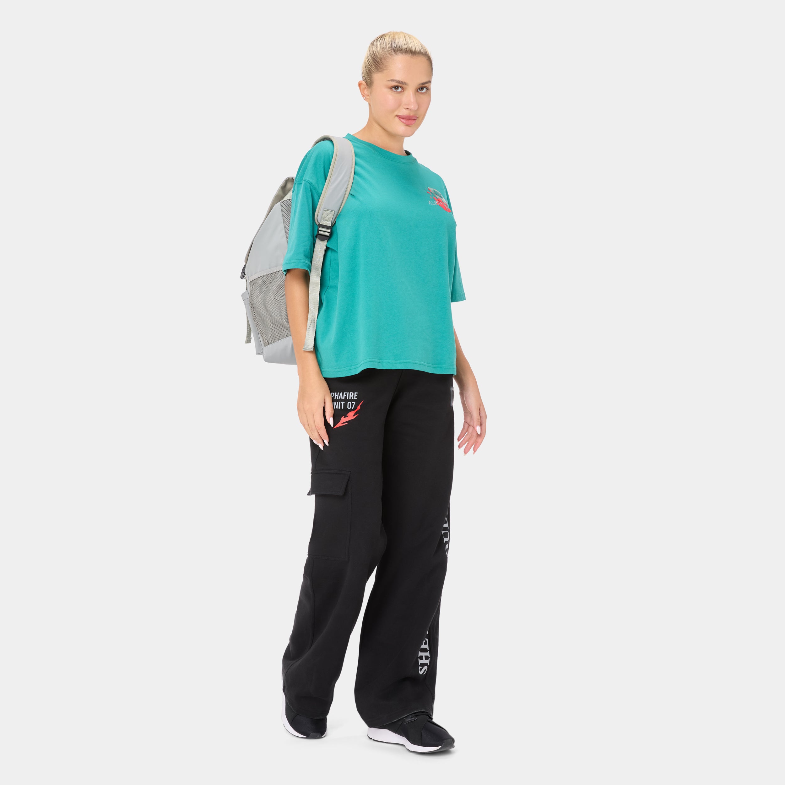 ALPHAFIRE OVERSIZED T-SHIRT — ROUGE GREEN — Full-body ¾ side view, teal oversized tee with black cargo pants, model wearin...