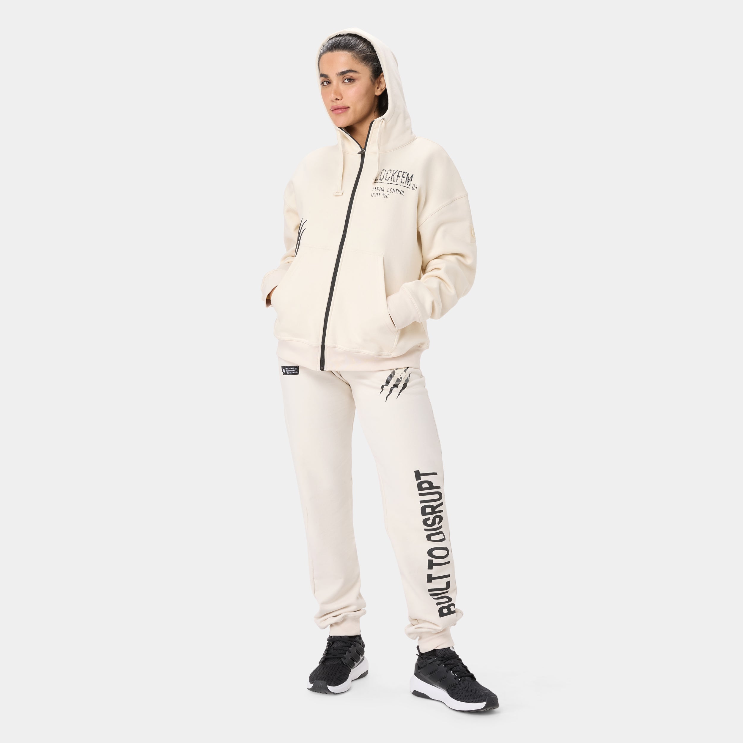 LOCKFEM_05 HOODIE — TACTICAL BEIGE — Full-body front/side view, cream zip hoodie with matching cream joggers reading Built T