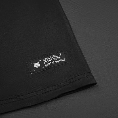 OPERATOR_77 OVERSIZED TEE — WAR BLACK — Flat-lay close-up, black tee Operator_77 Silent Work Brutal Output woven hem label w