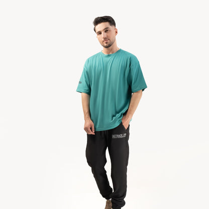 OPERATOR_77 OVERSIZED TEE — ROUGE GREEN — Full-body front view on male model, white background, teal tee with RUN sleeve tex